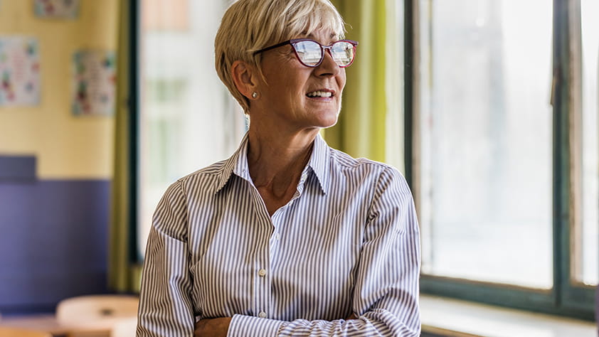 Confident teacher with crossed arms in the classroom