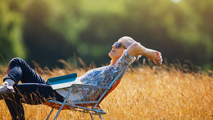 Woman relaxing with book in a sunny field