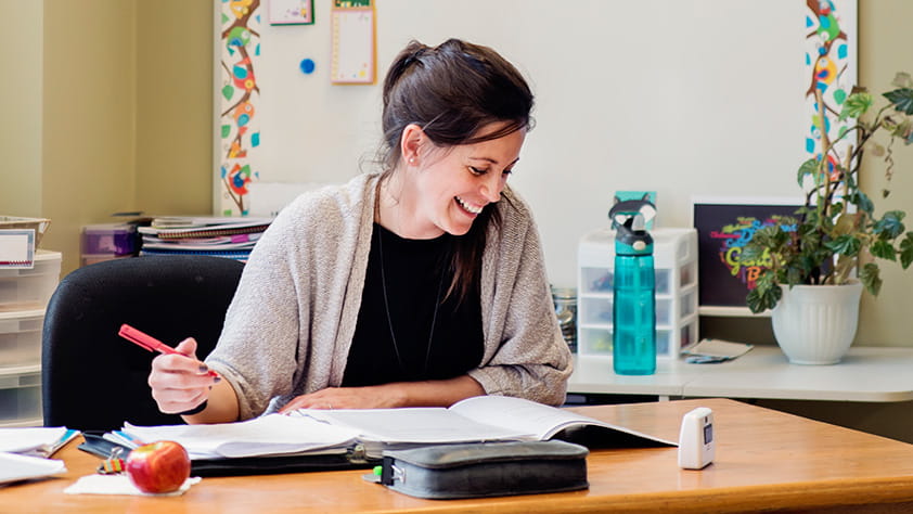 Teacher working at her desk in empty classroom