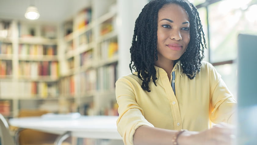 Woman in Library Typing on Computer