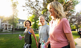 Smiling women walking for exercise in a sunny park