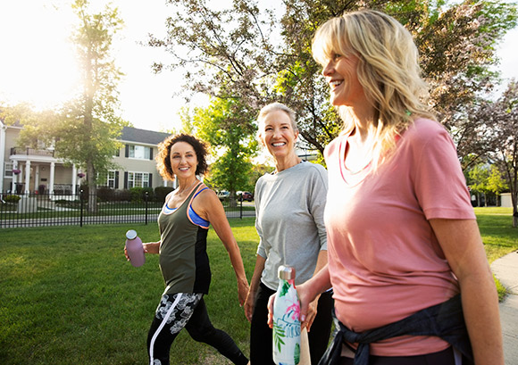 Smiling women walking for exercise in a sunny park