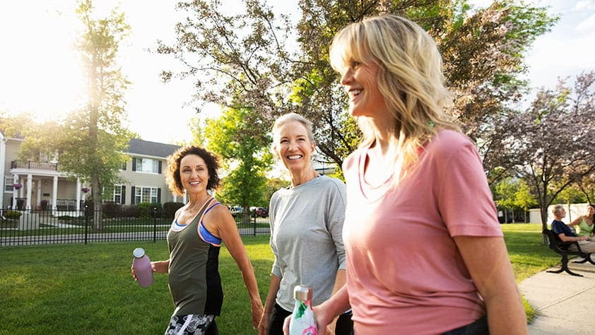 Smiling women walking for exercise in a sunny park