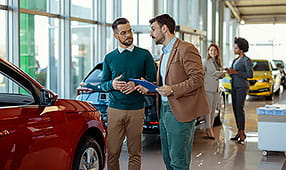 Two Men in a Car Showroom Discussing Buying a Car