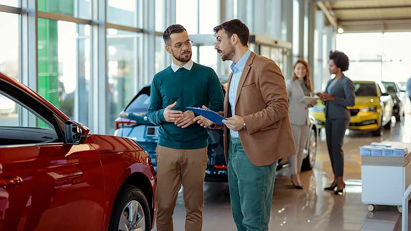 Two Men in a Car Showroom Discussing Buying a Car