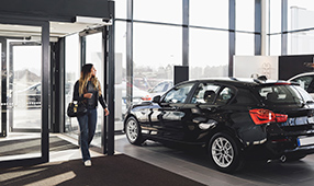 Woman Entering Into New Car Dealership