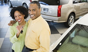 Couple at a Car Dealership Holding the Key to Their New Car
