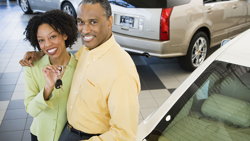 Buy a Car with Confidence Using This 14-Point Checklist - Couple at a Car Dealership Holding the Key to Their New Car