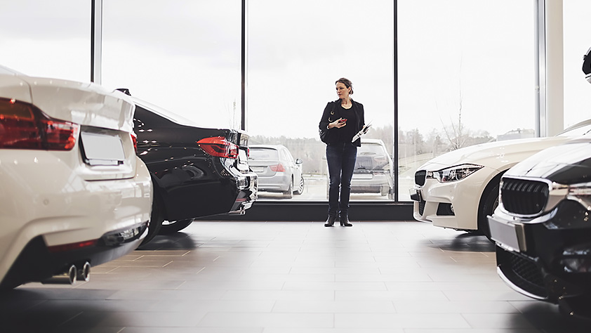 Woman Standing Amidst Cars in a Showroom