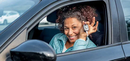 Smiling African-American Woman Sitting in Her New Car Showing Off Car Keys