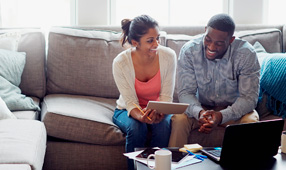 Young couple going through paperwork together on the sofa at home