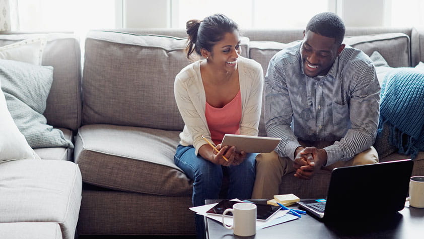 Young couple going through paperwork together on the sofa at home