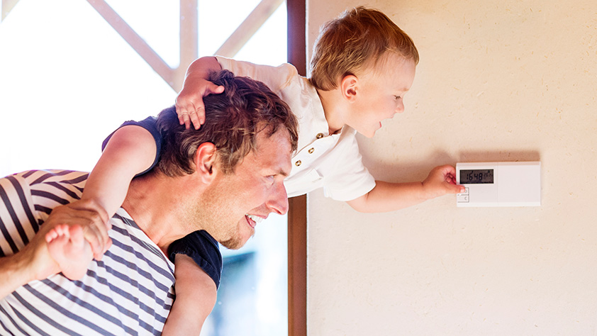 Father Carrying Son on Shoulders, Adjusting Thermostat
