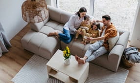 Family with small daughters sitting on sofa in their new home