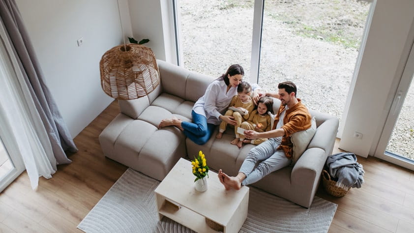 Family with small daughters sitting on sofa in their new home