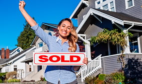Woman Holding Sold Sign Outside of House