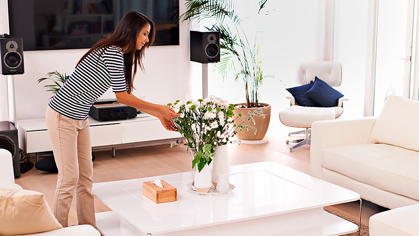 Woman placing a vase of white flowers on her living room table