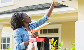Unexpected Costs of Owning a Home - Woman Fixing Home Exterior