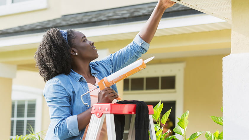 Unexpected Costs of Owning a Home - Woman Fixing Home Exterior