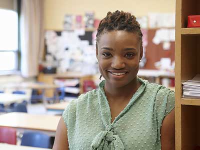 Student Loan Debt - Young Confident Teacher in Her Classroom
