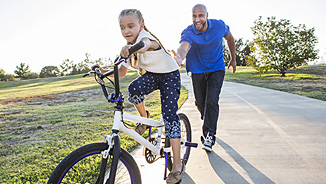 NEA Group Term Life Insurance - Father Teaching His Daughter to Ride a Bike