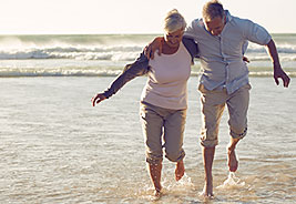 Happy Older Couple Running on the Beach at Dusk