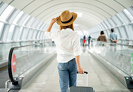 Woman Walking Through an Airport - NEA Travel: Flights
