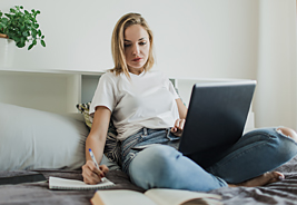 Young Woman Sitting in Bed Using Laptop
