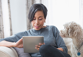 Woman reading newsletter on a digital tablet with her dog
