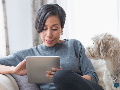 Woman reading newsletter on a digital tablet with her dog