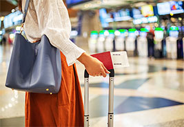 NEA Travel: Airfare - Woman at check-in counter in airport terminal, with luggage and passport