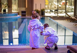 NEA Travel: Hotels - Cute little sister and brother holding hands wearing bathrobes while checking the water temp at the hotel pool