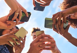 Low Angle Shot of a Group of Cheerful Friends Texting on Their Cellphones Outside During the Day
