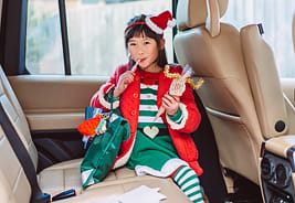 Little Girl in a Holiday Costume Sitting in the Back of a Car