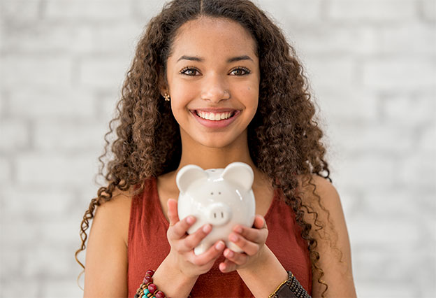 Happy young woman holding a piggy bank full of savings