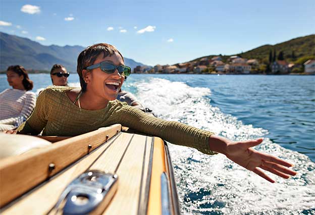 Cheerful young woman enjoying a boat ride with friends on a sunny day