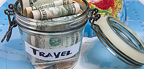 Money in a Jar Labeled Travel Sitting on a Map