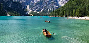 Travel: Row boat floating in a lake with clear blue water surrounded by mountains