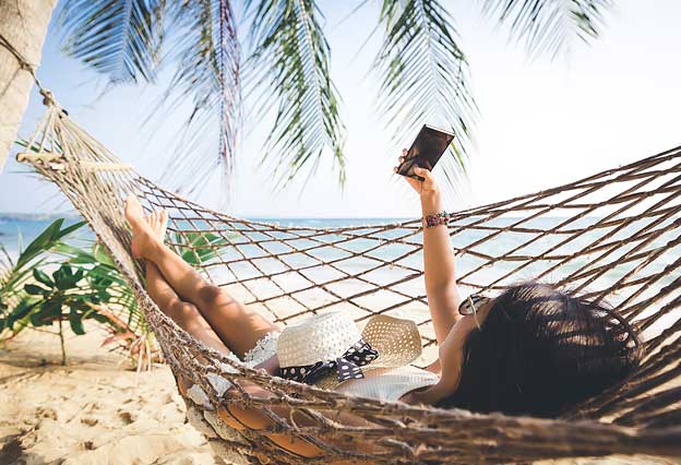 Sign Up for the NEA Travel Newsletter - Woman with Mobile Phone Relaxing in a Hammock