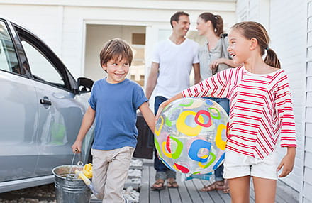 Happy Family with Beach Gear Standing Next to Their Car - NEA Auto and Home Insurance Program