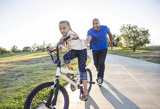 Father teaching daughter to ride her bike