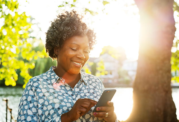 Smiling woman with smart phone outside