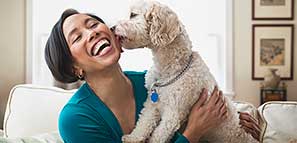 Pet Insurance: Woman smiling while holding her dog who is licking her cheek