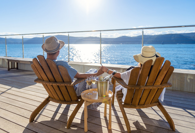 NEA Travel: Cruises - Couple relaxing in chairs on ship deck