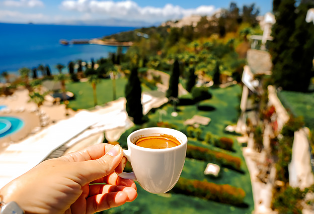 NEA Travel: Resorts - Hand Holding a Cup of Coffee, Overlooking a Sea View