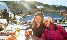 NEA Travel: Resorts - Mother and daughter laughing and having drinks outside at a ski resort