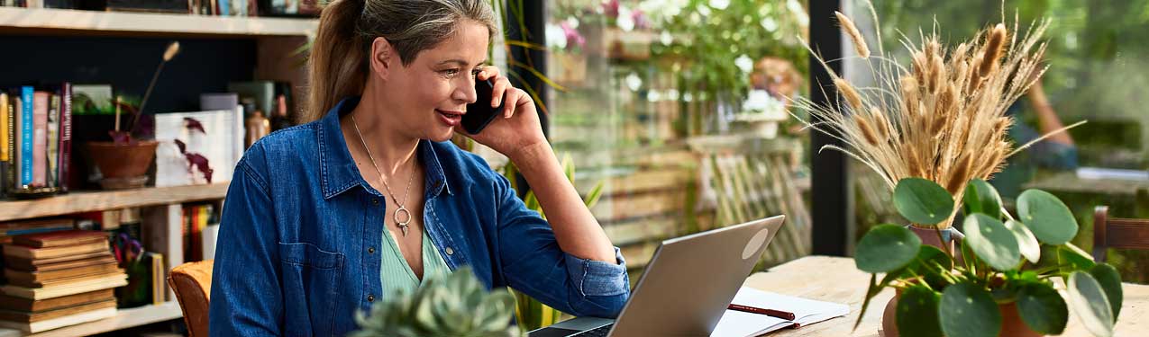 Woman Using a Mobile Phone in Front of a Laptop