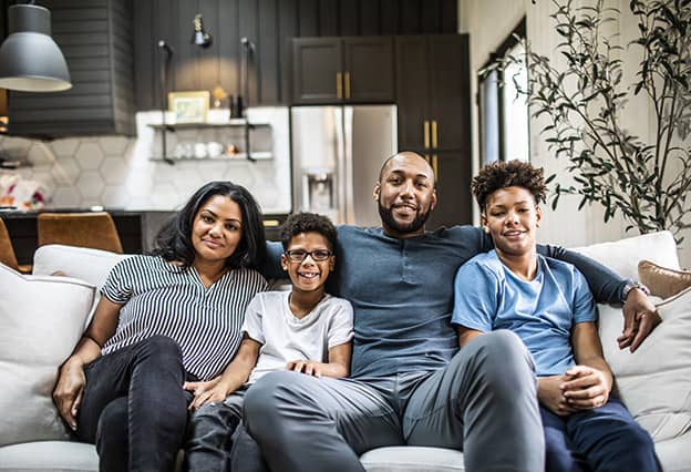 Familia de cuatro personas sentada en un sofá en casa