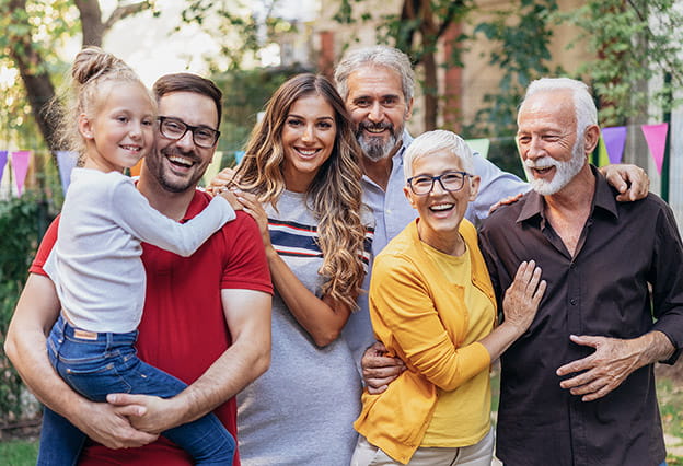 Tres generaciones de una familia mirando a cámara y sonriendo