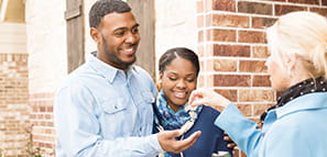 Una joven pareja recibe de su agente inmobiliario la llave de su primera casa